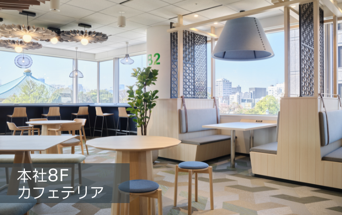 カフェテリア。大きな窓とテーブル席のある共有空間